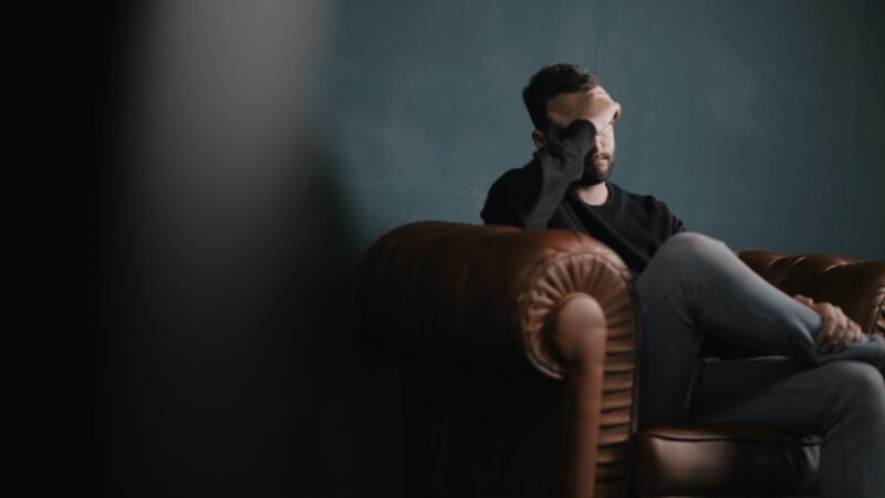 man on chair with hand over face