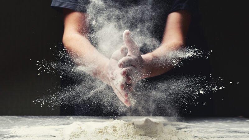 Clap hands of baker with flour in kitchen