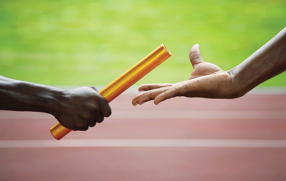 Two men passing golden baton in stadium